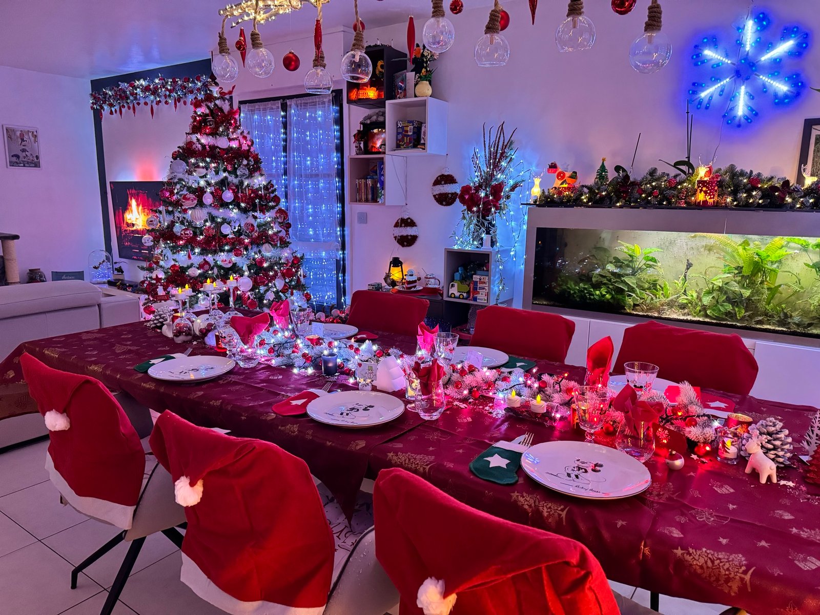 Salon et table de Noël décorés en rouge et blanc, avec un grand sapin illuminé