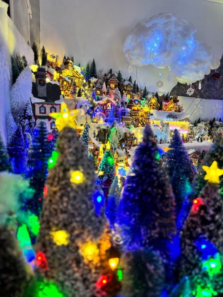 Sapins enneigés et guirlandes lumineuses devant les maisons du village de Noël.